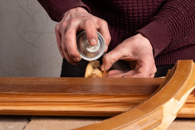 Master sprays varnish on a wooden door restoration