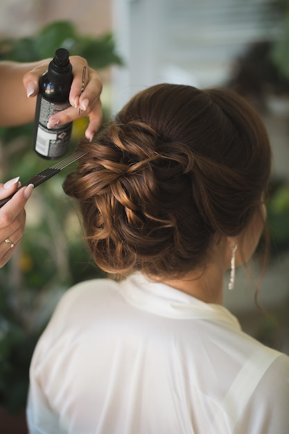 写真 マスタースタイリストはスプレーラッカー固定を使用して花嫁の結婚式のヘアスタイルを作ります