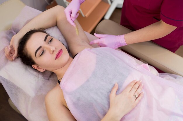 Master of sugaring puts paste on the girl's armpits Professional woman at spa beauty salon