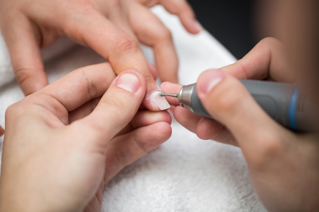 Photo the master uses an electric machine to remove the nail polish during manicure in the salon. hardware manicure. concept of body care