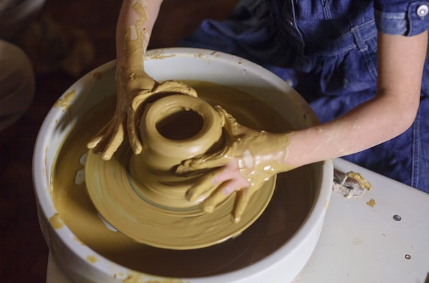 The master with the child molds a clay jug.