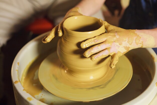 The master with the child molds a clay jug.