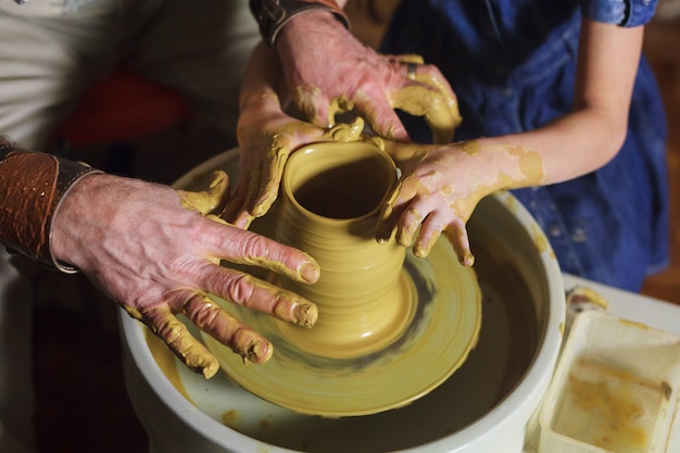 The master with the child molds a clay jug.