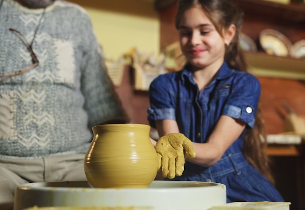 The master with the child molds a clay jug.