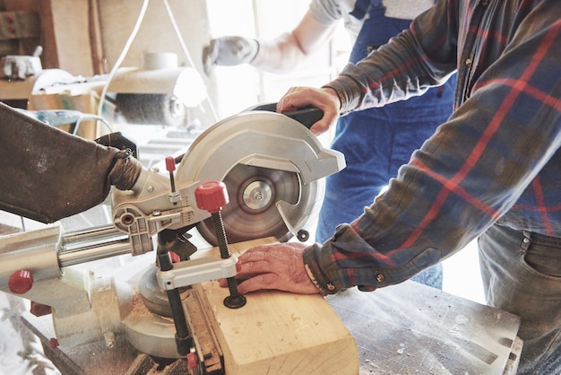 Photo master in a work suit using a grinder on a sawmill.