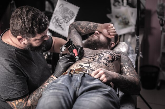 Master working on professional tattoo machine device in tattoo studio