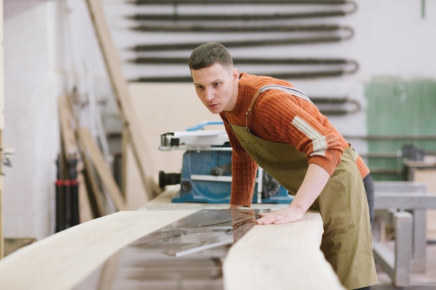 Il maestro lavora su una rettificatrice per piani nell'officina di carpenteria