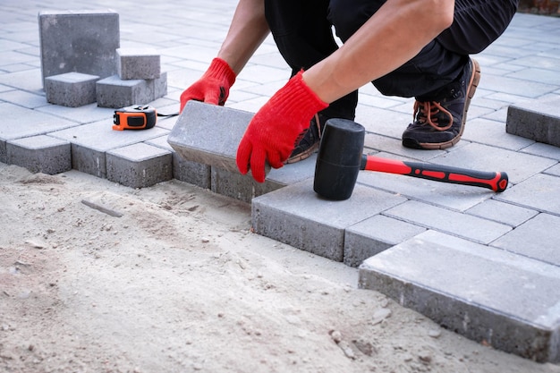 The master in yellow gloves lays paving stones