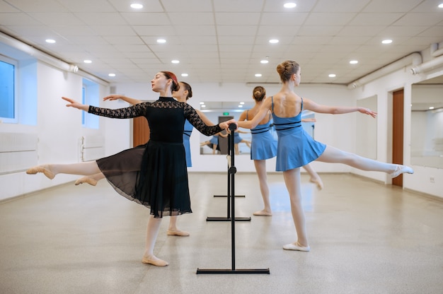 Master and young ballerinas exercise at the barre in class