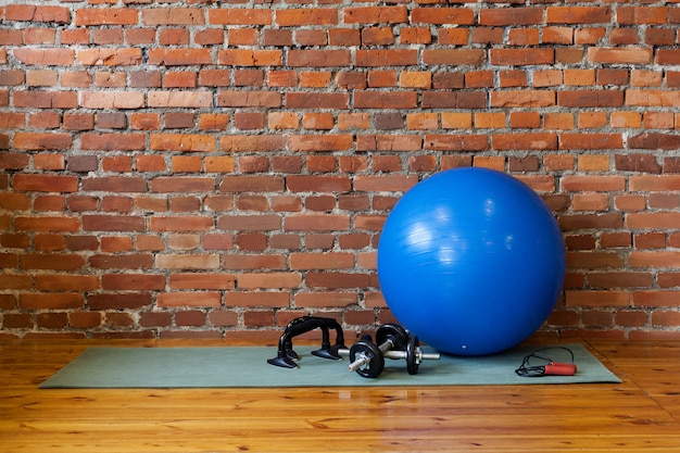 Photo mat, fitball, rope, dumbbells and stand push-upse on floor in gym