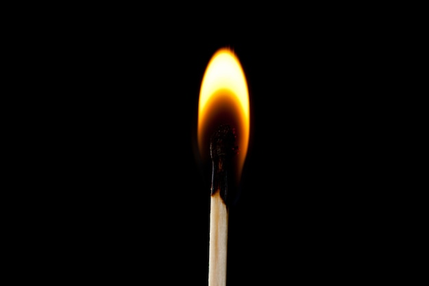 Match on fire against a black background