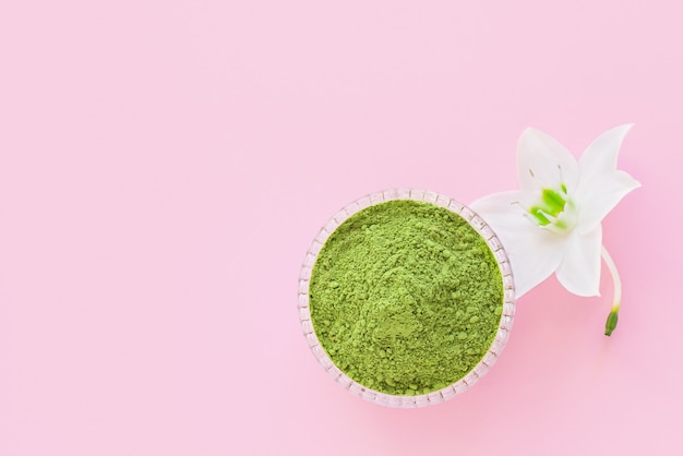 Matcha droog groen poeder op een roze achtergrond voor het maken van Japanse natuurlijke thee.