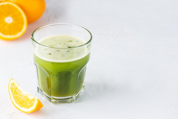 Matcha en sinaasappelsap drinken in een glas op een lichttafel. Horizontale oriëntatie, kopieer ruimte.