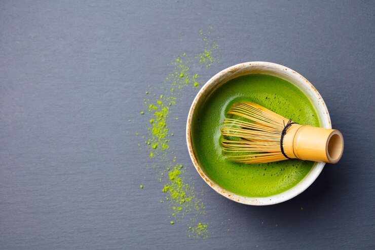 Photo matcha green tea cooking process in bowl with bamboo whisk slate background top view copy space