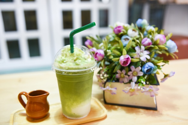Matcha green tea with milk on plastic glass on the table in a cafe