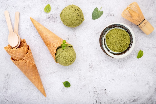 Matcha groene thee-ijs met wafelkegel en muntblaadjes setup op witte stenen achtergrond