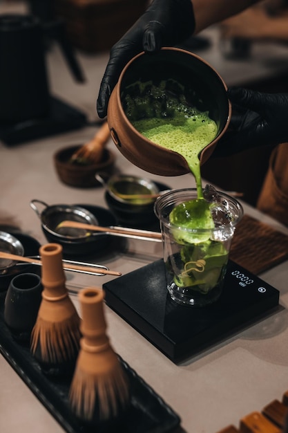 Matcha Japanese green tea making process Female hands pouring matcha into a plastic cup