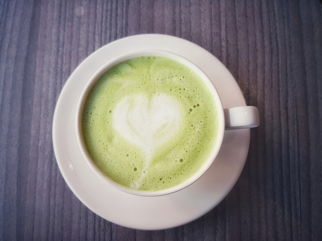 Matcha latte green tea foam art is heart in a brown cup