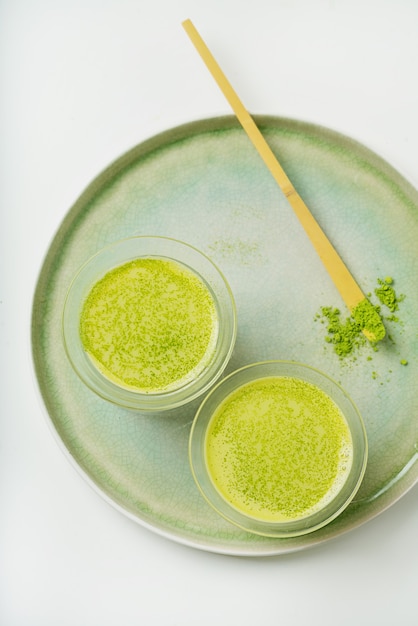 Matcha latte healthy coffee alternative on a ceramic tray decorated with matcha powder and scoop chashaku. Flat lay. Top View