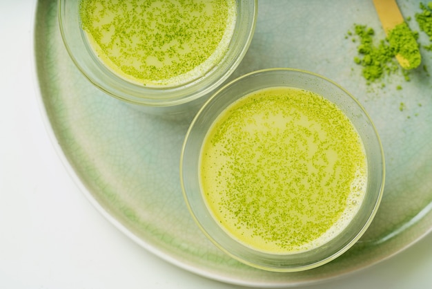 Matcha latte healthy coffee alternative on a ceramic tray decorated with matcha powder and scoop chashaku. Flat lay. Top View