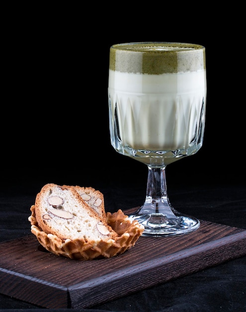 Matcha latte in een glas met amandelcrackers op een donkere achtergrond