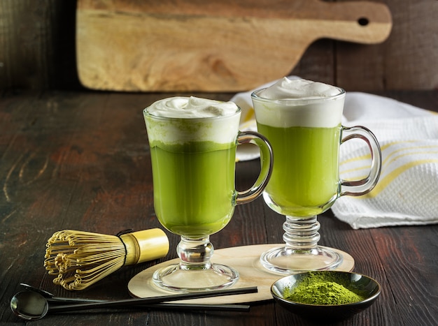 Matcha latte met crème schuim in glazen, bamboe garde en matcha poeder