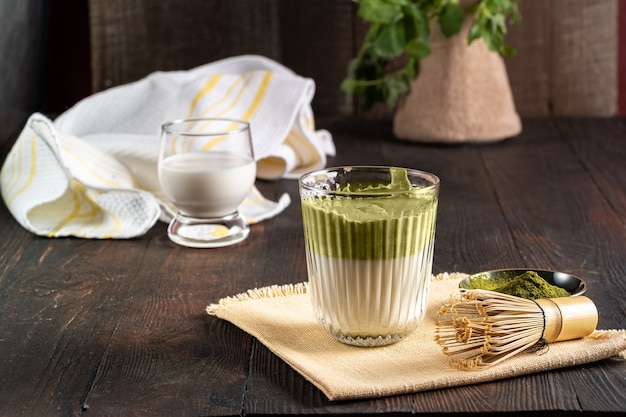 Tè matcha latte, polvere verde su uno sfondo di legno.