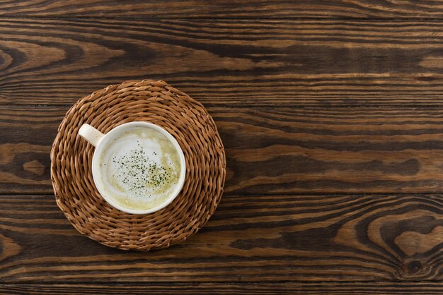 Matcha latte tea with coconut milk and hemp seeds in a mug on a wooden table