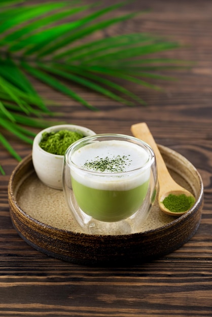 Matcha latte tea with hemp seeds and coconut milk in a glass on a tray.