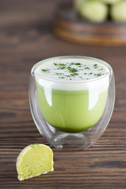 Matcha latte thee in een glas met truffel op een houten tafel Suikergluten en lactosevrij