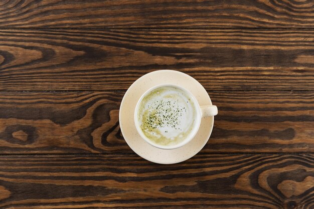Matcha latte-thee met kokosmelk in een kopje. Horizontale oriëntatie, bovenaanzicht.