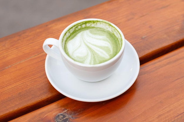 Matcha latte in white cup on wooden table