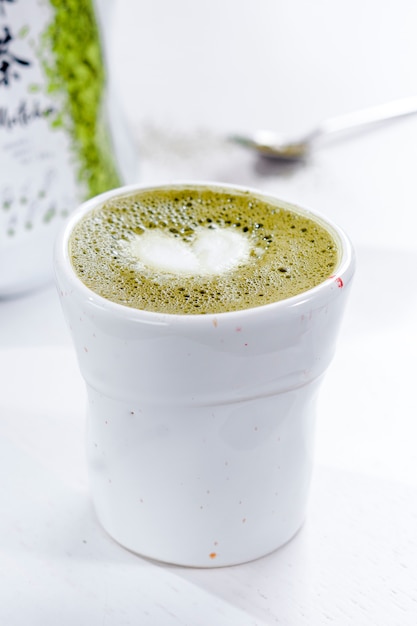 Matcha latte in white mug with froth in a heart shape