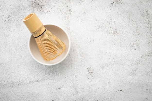 Matcha set bamboo matcha whisk set up on white concrete.