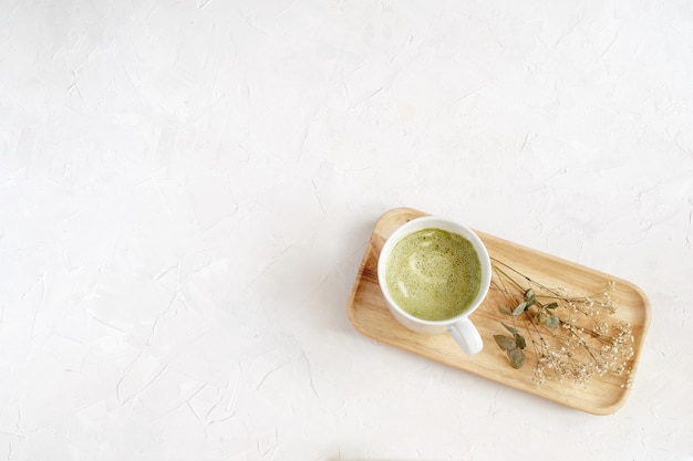 Matcha in white cup on wooden tray