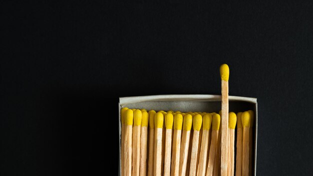 Matches with yellow heads in a box, dark background.