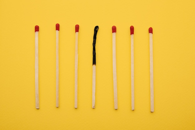 Matchsticks with one burned out on a yellow background Burnout concept