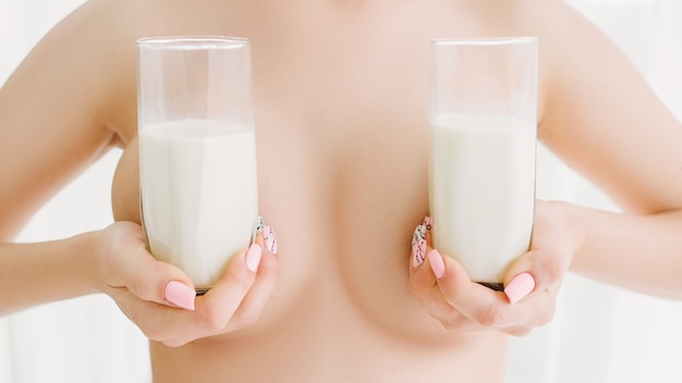 산모의 건강. 모유 수유 영양. 우유 안경으로 가슴을 덮고 있는 누드 여자.