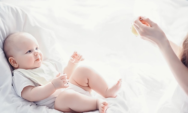 Концепция материнства Молодая мать кормит своего маленького ребенка Первая приманка и кормление грудью Семья в белой одежде