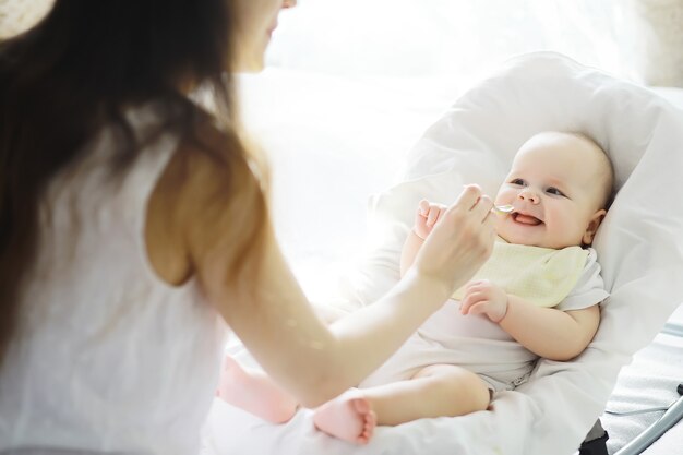 Maternity concept. A young mother feeds her little baby. First lure and breastfeeding. Large family in white clothes.