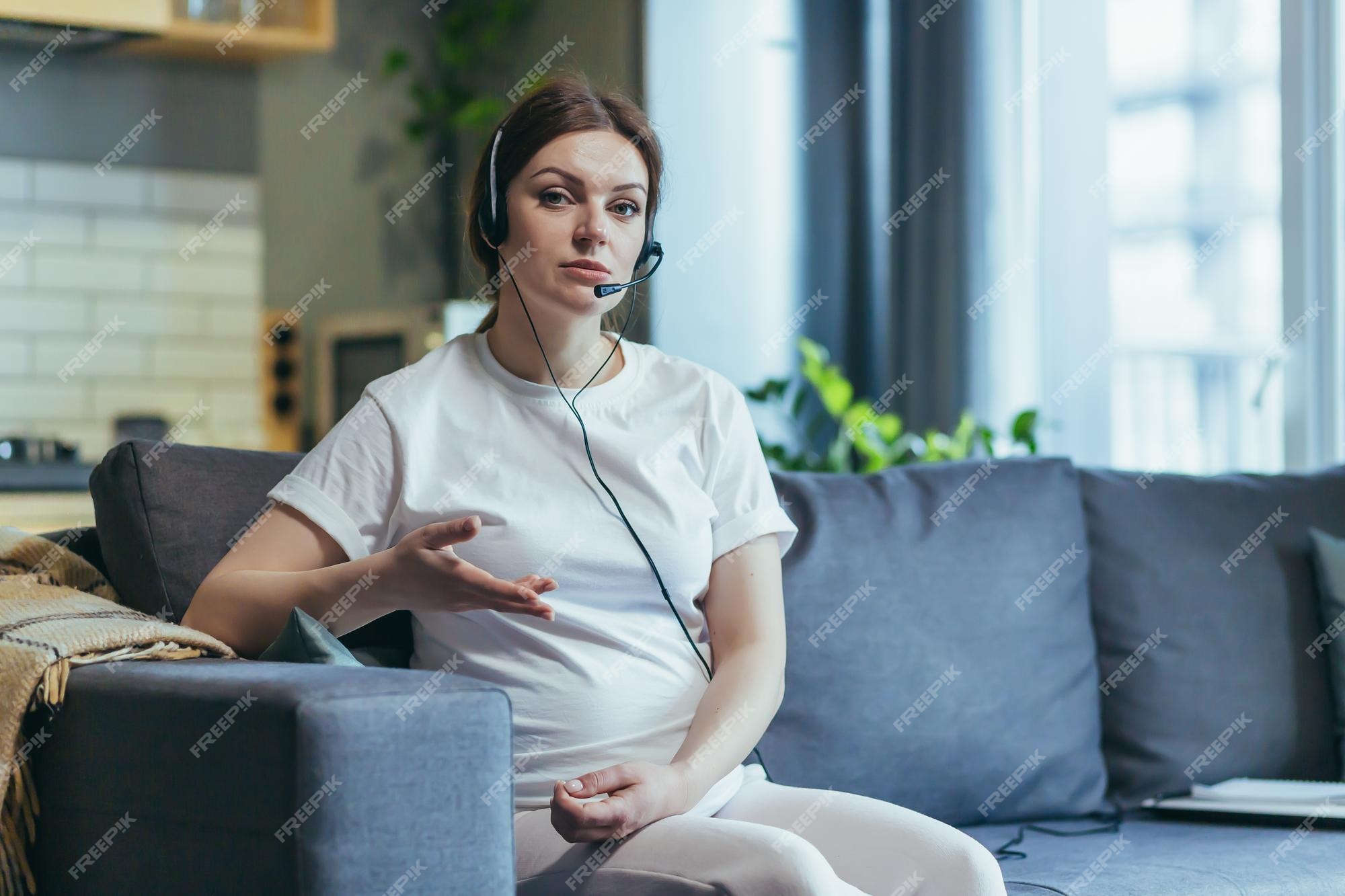 Premium Photo | Maternity leave work pregnant freelancer woman sitting at  home on sofa with laptop and in headphones in home clothes works on the  computer looking at the camera