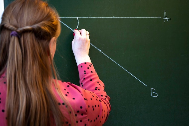 Foto un insegnante di matematica spiega la lezione agli studenti vicino alla lavagna