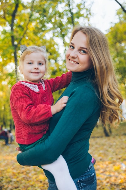 Foto mather con la piccola figlia del bambino che gioca nel parco pubblico della città di autunno