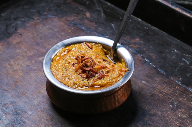 Mathrooba Chicken haleem halim은 튀긴 양파와 함께 테이블 아랍 음식에 대한 빨간색 매트 상단 보기에 격리된 접시에 제공됩니다.