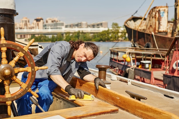 Matroos die hout poetst en jacht repareert