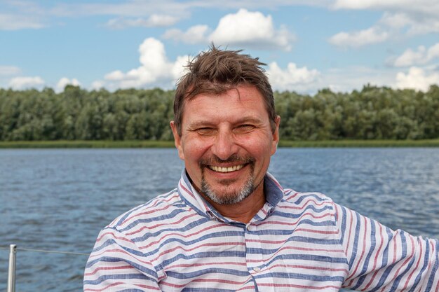 Matroos man in een pet op een boot onder zeil tegen de lucht en het water