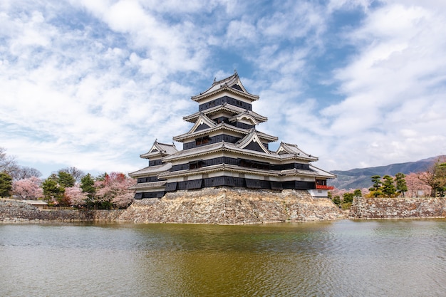 Matsumoto castle in spring season surrounded by water under cloud sky