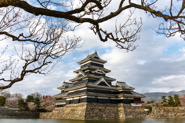 Matsumoto castle in spring season surrounded by water under cloud sky