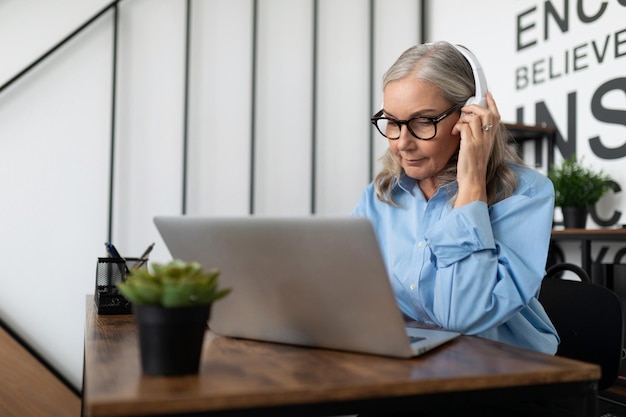 Mature adult boss woman with gray hair has a conversation using internet and headset