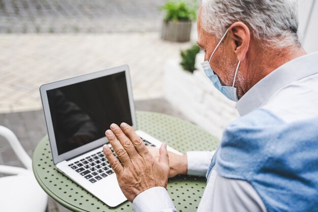 Photo mature adult using his computer laptop at the terrace